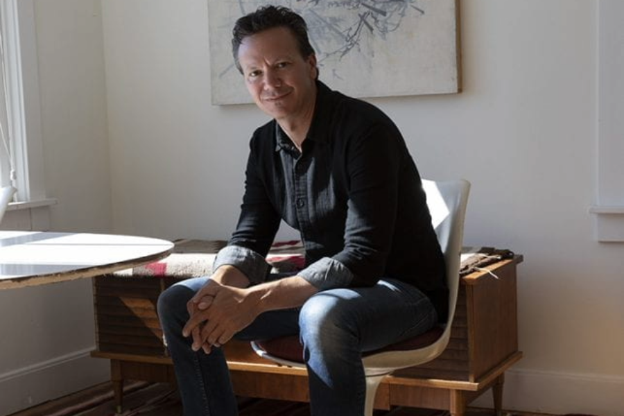 Photo of Caleb Smith seated next to small table.
